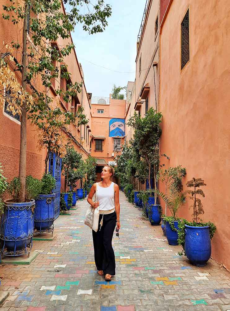 A woman (me) wearing a white sleeveless top and black floaty pants walking on the street of Marrakech. Make sure you add a pair of floaty harem pants to yuor Morocco packing list. 