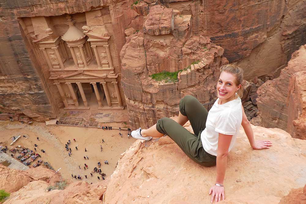 photo of the Treasury at Petra from above with a woman wearing a baggy t-shirt and cropped green trousers