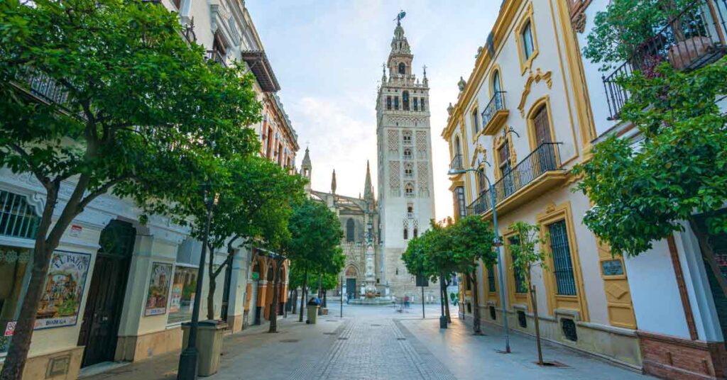 Image of the Giralda in Seville along a pedestrianised street, this is the featured image for an article about the best things to do in seville with 35 things to add to your seville bucket list.