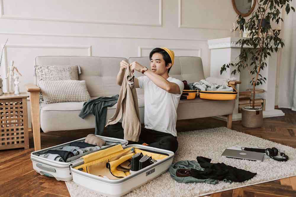 A man packing his clothes in a living room for his travel