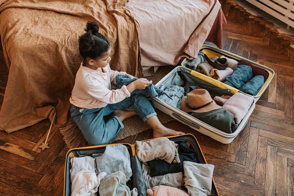 Little girl packing her clothes in a suitcase